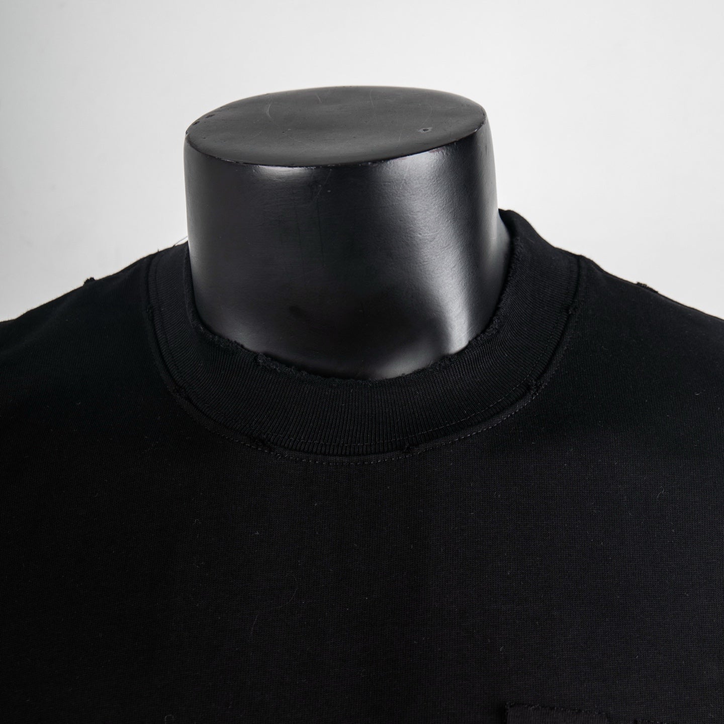 Black crew-neck short-sleeve T-shirt neckline close-up on mannequin