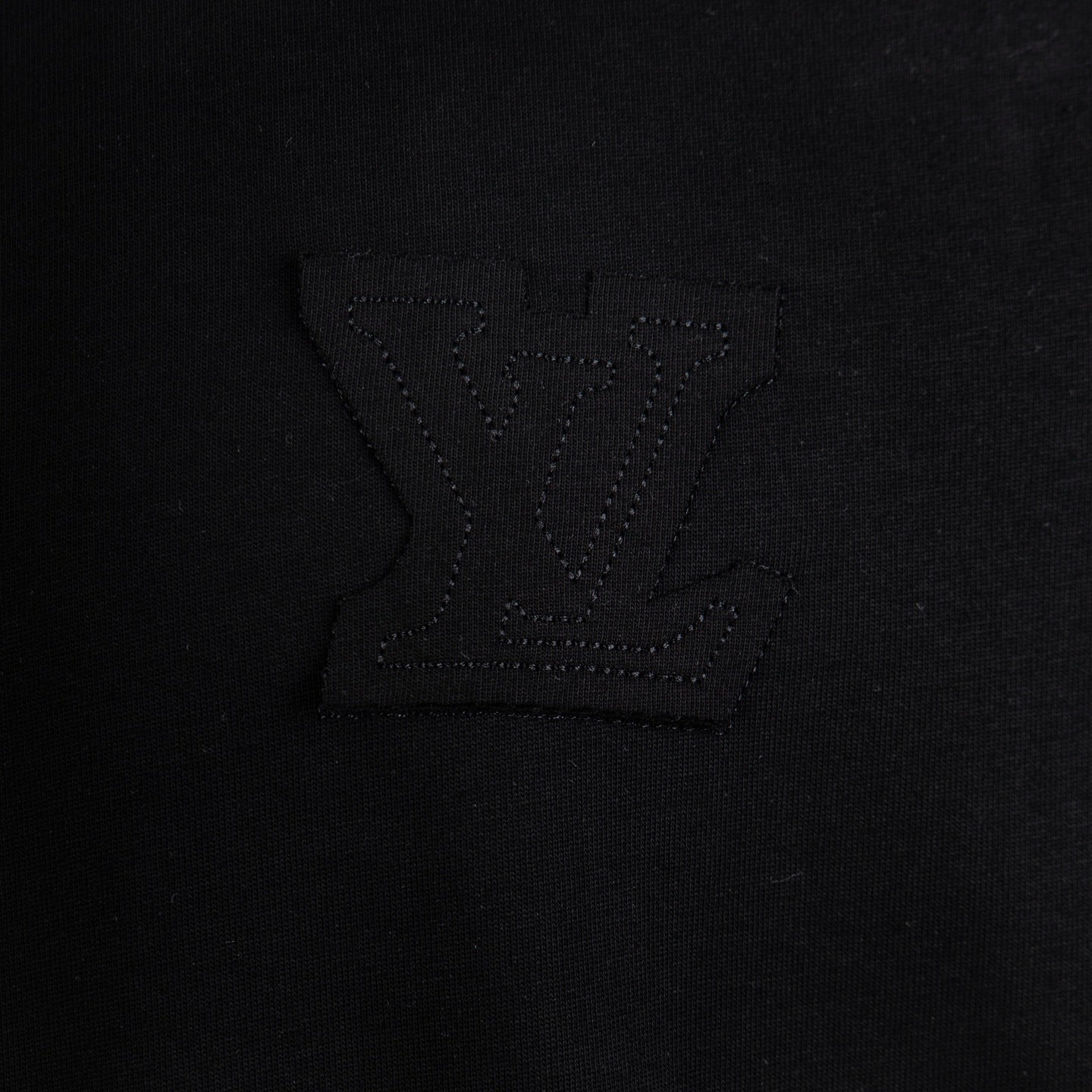 Black T-shirt chest area with embossed logo embroidery detail