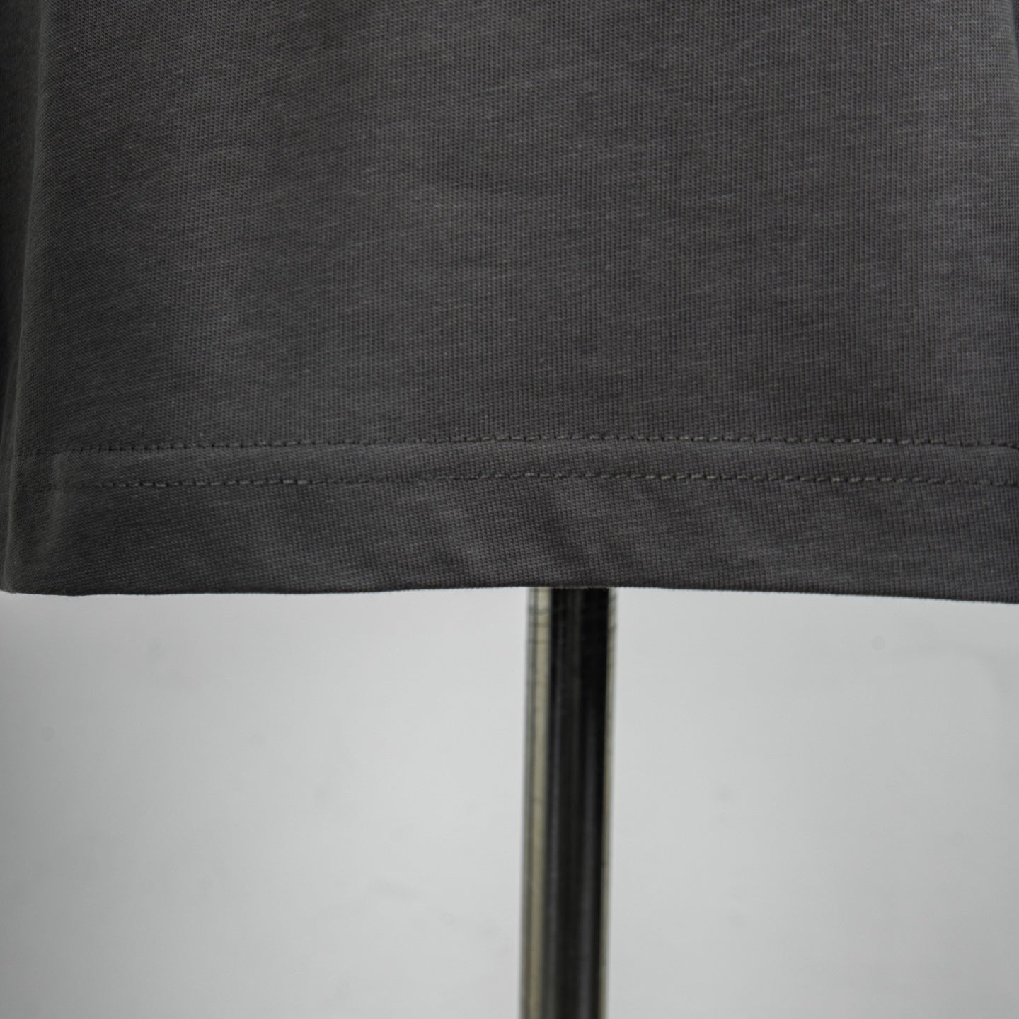 Dark gray T-shirt hem stitching along the bottom edge