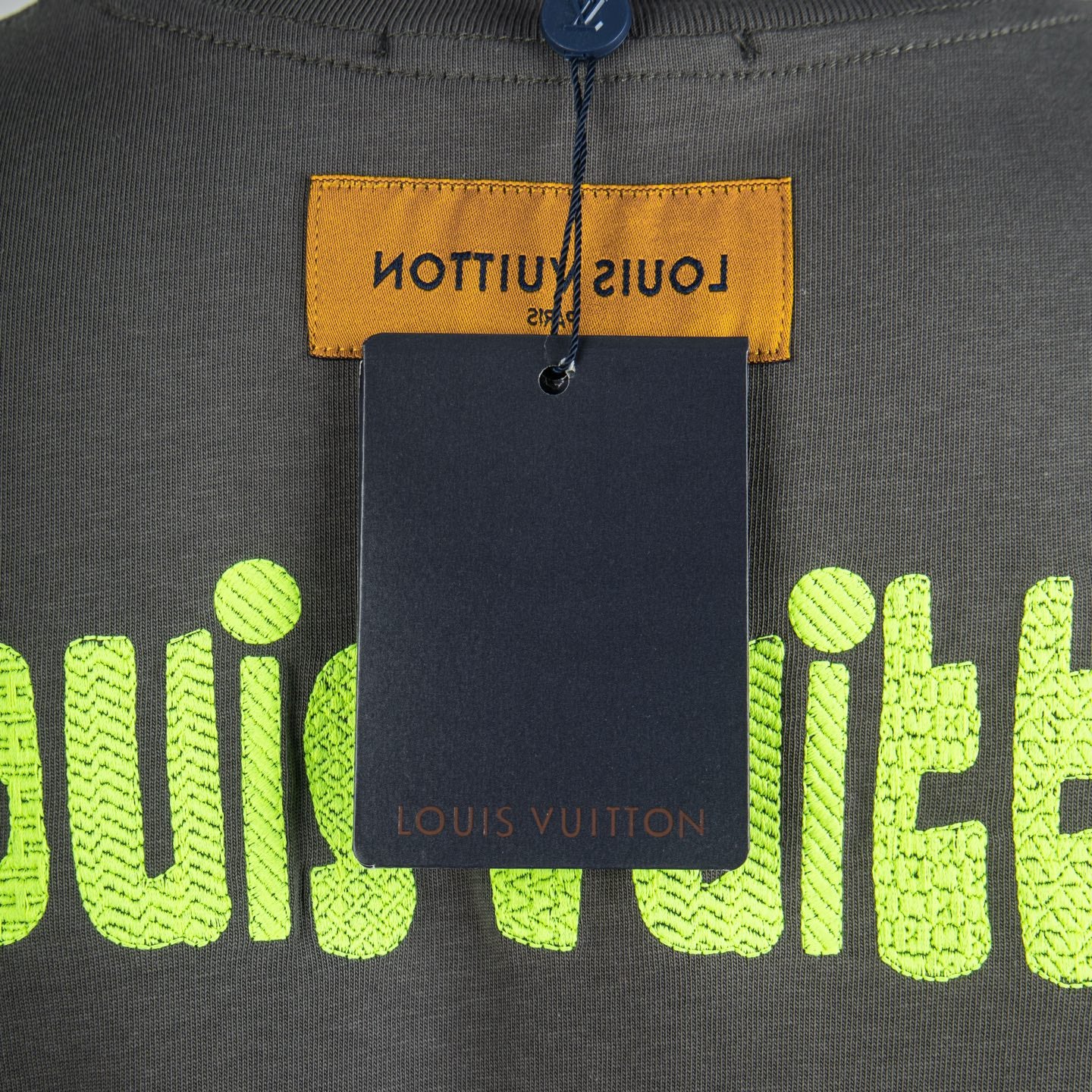 Charcoal T-shirt hang tag over neon green Louis Vuitton logo print
