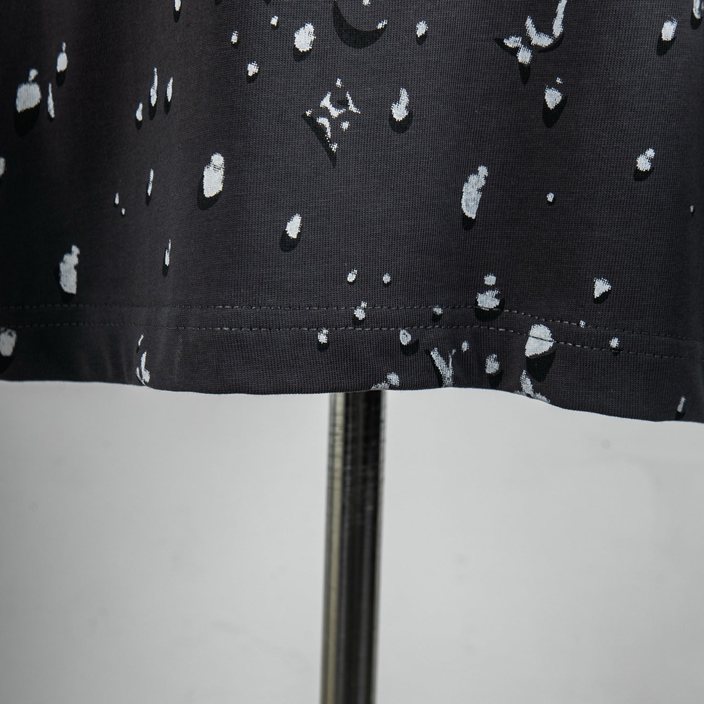 Black T-shirt hem with white logo pattern and stitched edge