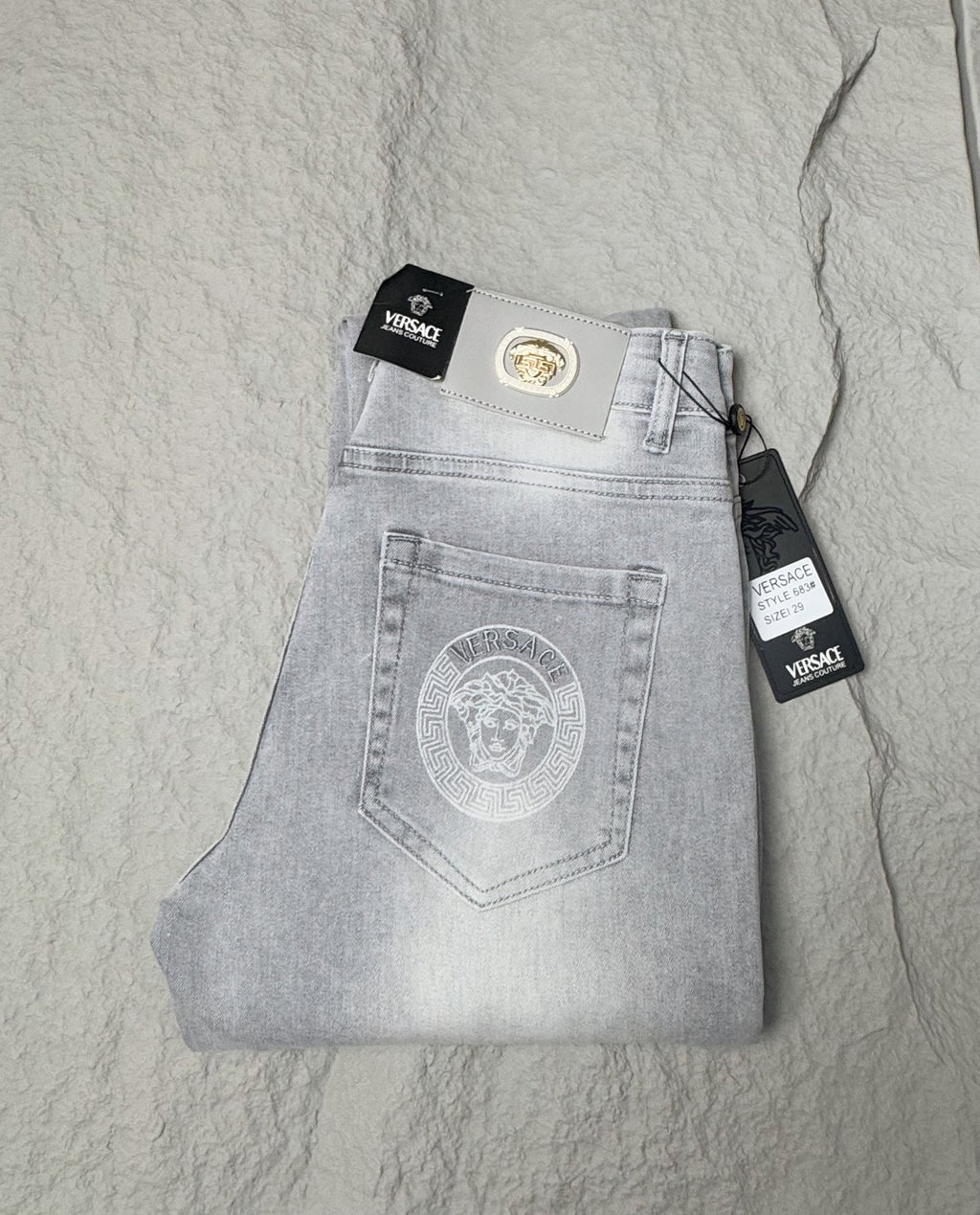 Light blue denim jeans with Versace waistband patch and front button fly