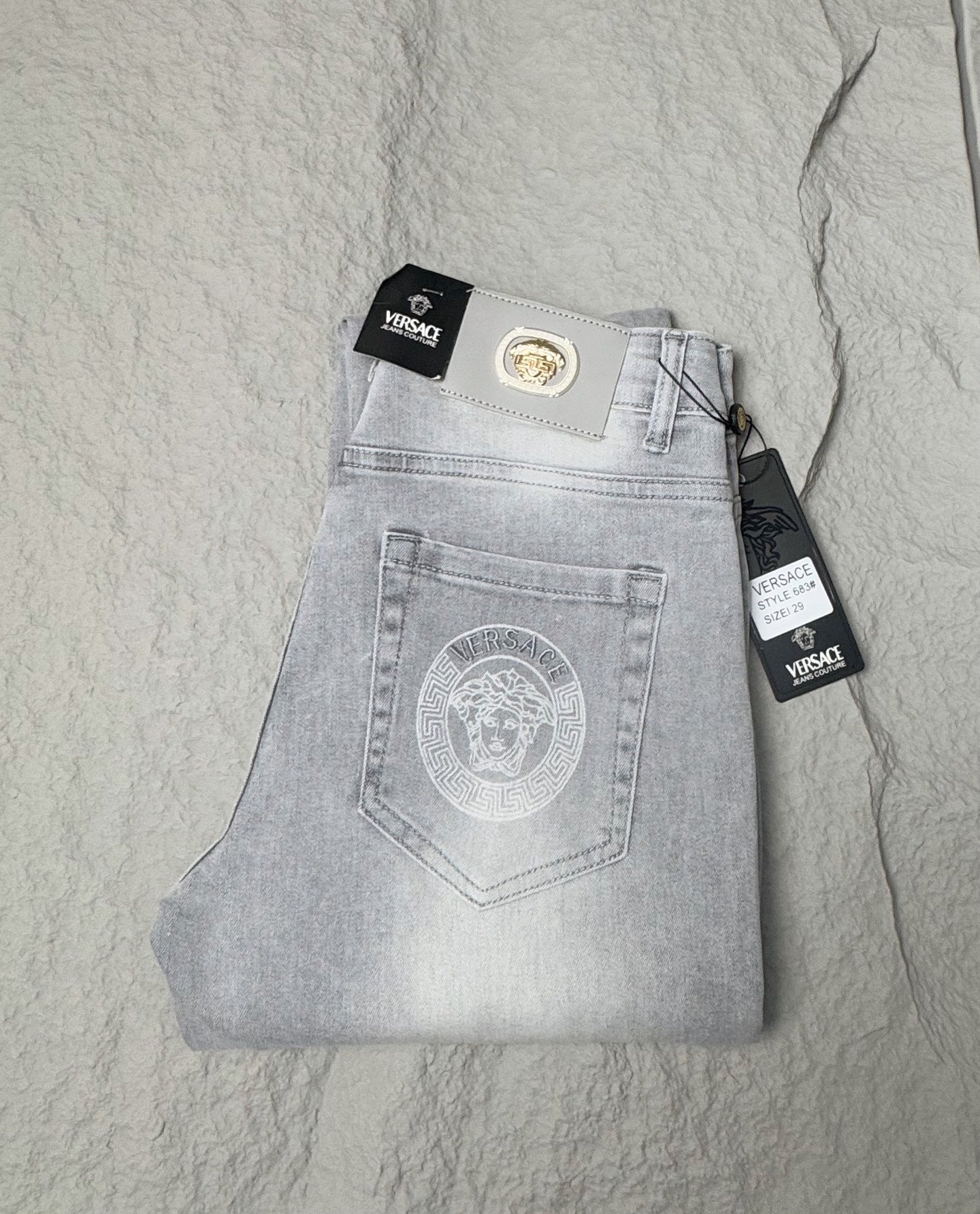 Light blue denim jeans with Versace waistband patch and front button fly