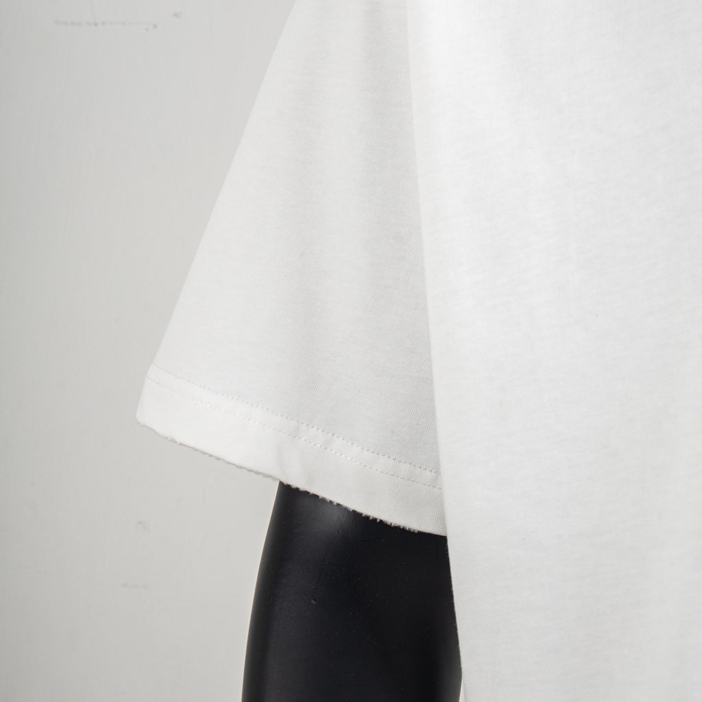 White T-shirt hem and side seam detail over a dark mannequin arm