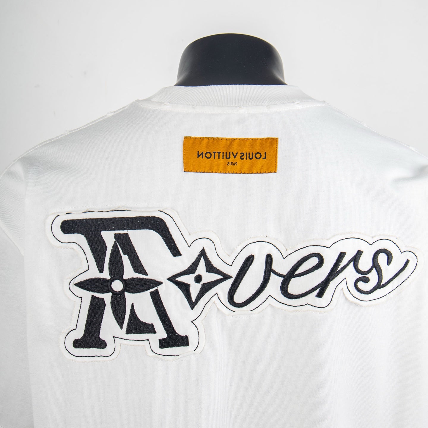 Back of white T-shirt with oversized cursive graphic and Louis Vuitton logo patch