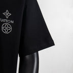Black T-shirt sleeve and side seam with rhinestone emblem on shoulder