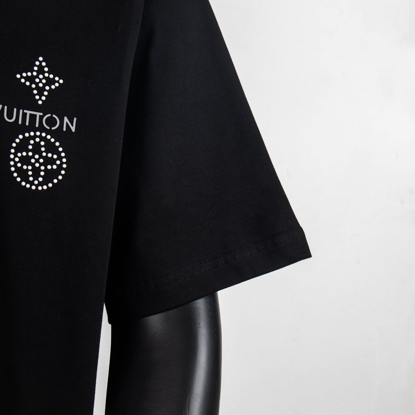 Louis Vuitton black T-shirt sleeve close-up with partial rhinestone emblem