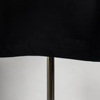 Black T-shirt hem with visible stitching and straight bottom edge