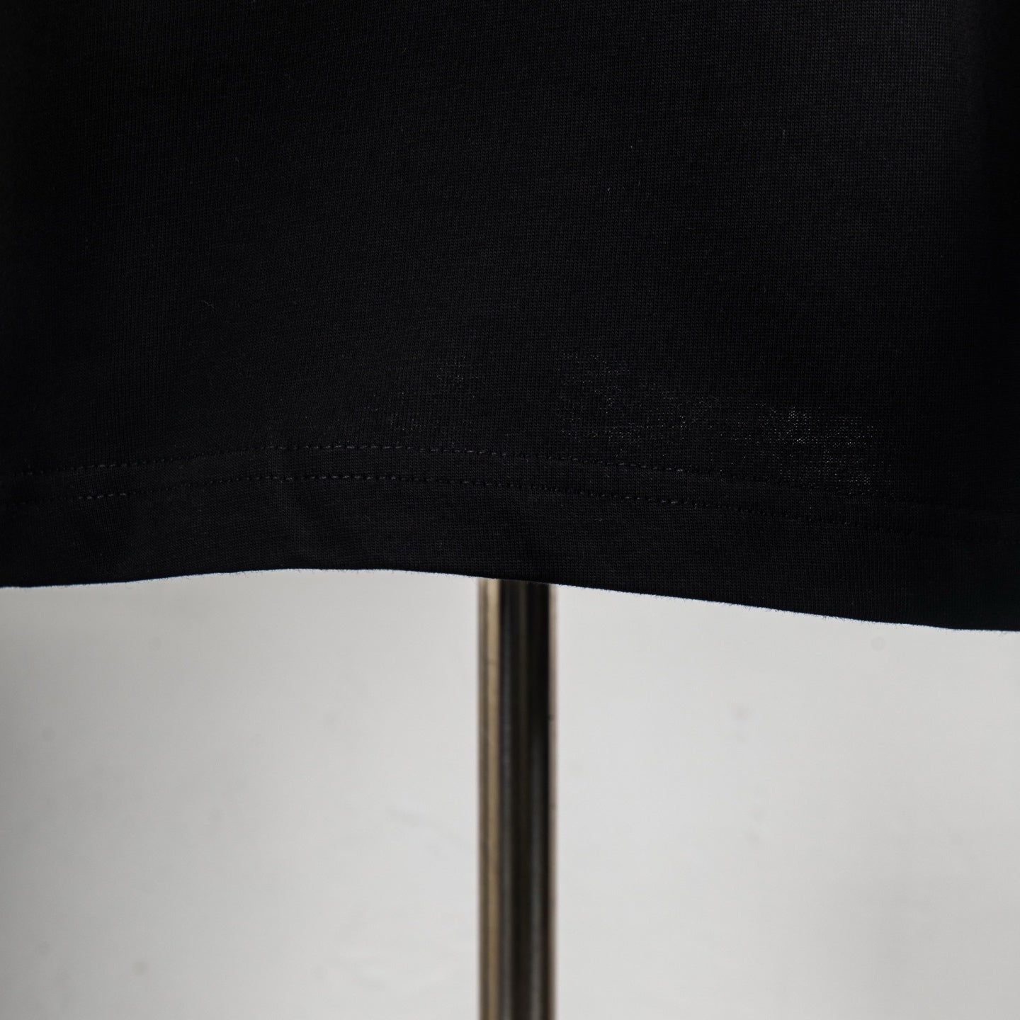 Black T-shirt hem with visible stitching and straight bottom edge