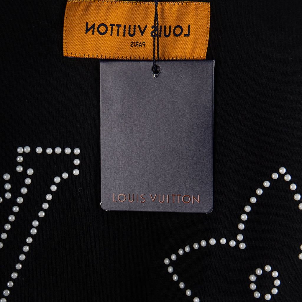 Louis Vuitton black T-shirt detail with yellow neck label, hangtag, and rhinestone dots