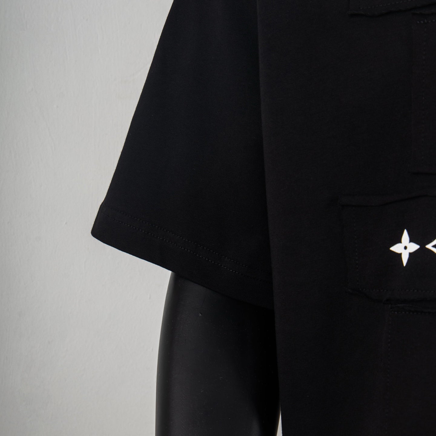 Black T-shirt sleeve and side pocket area with small white logo emblem