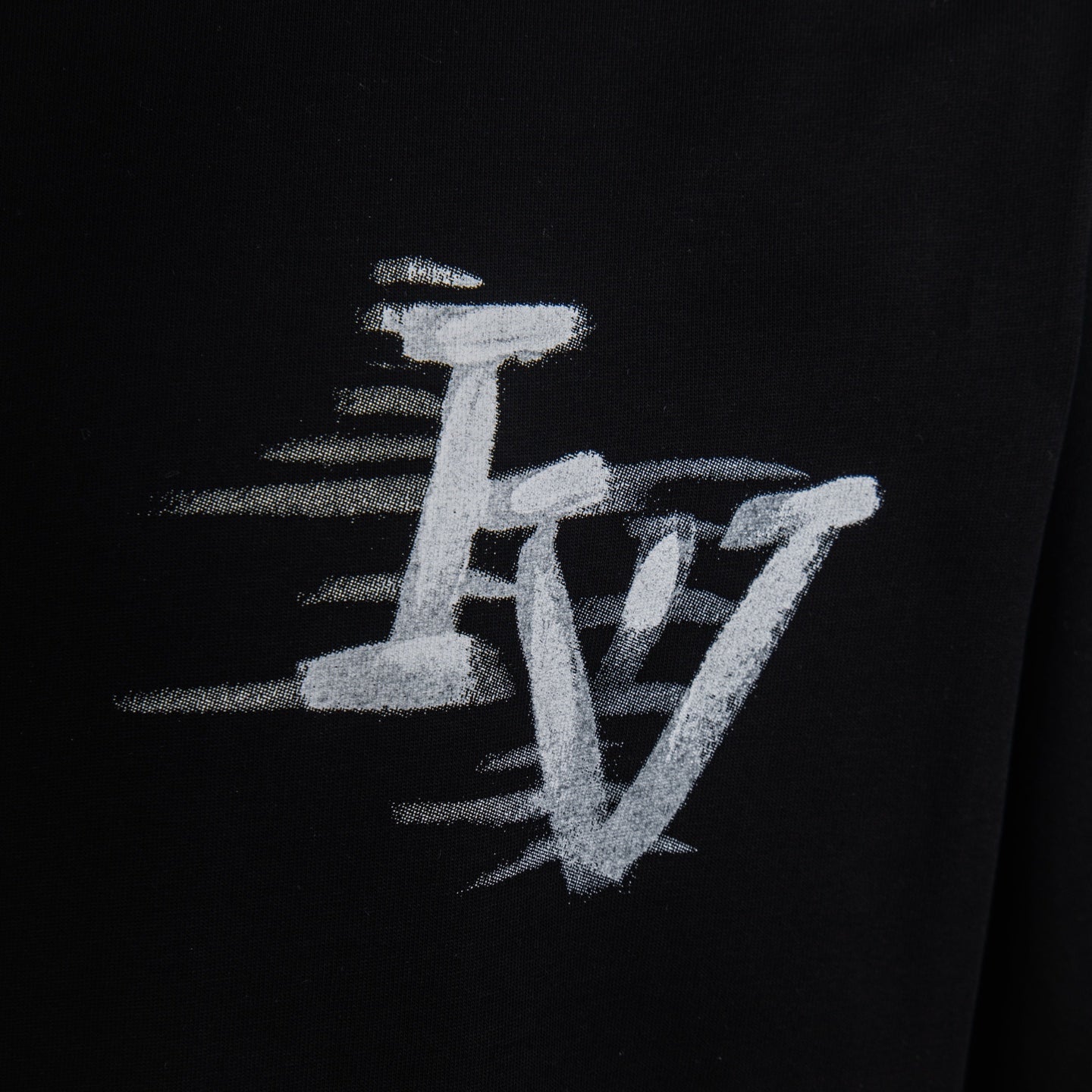 White LV script graphic detail on black T-shirt sleeve