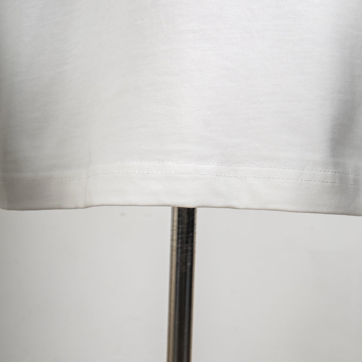 White T-shirt lower hem and visible stitching close-up