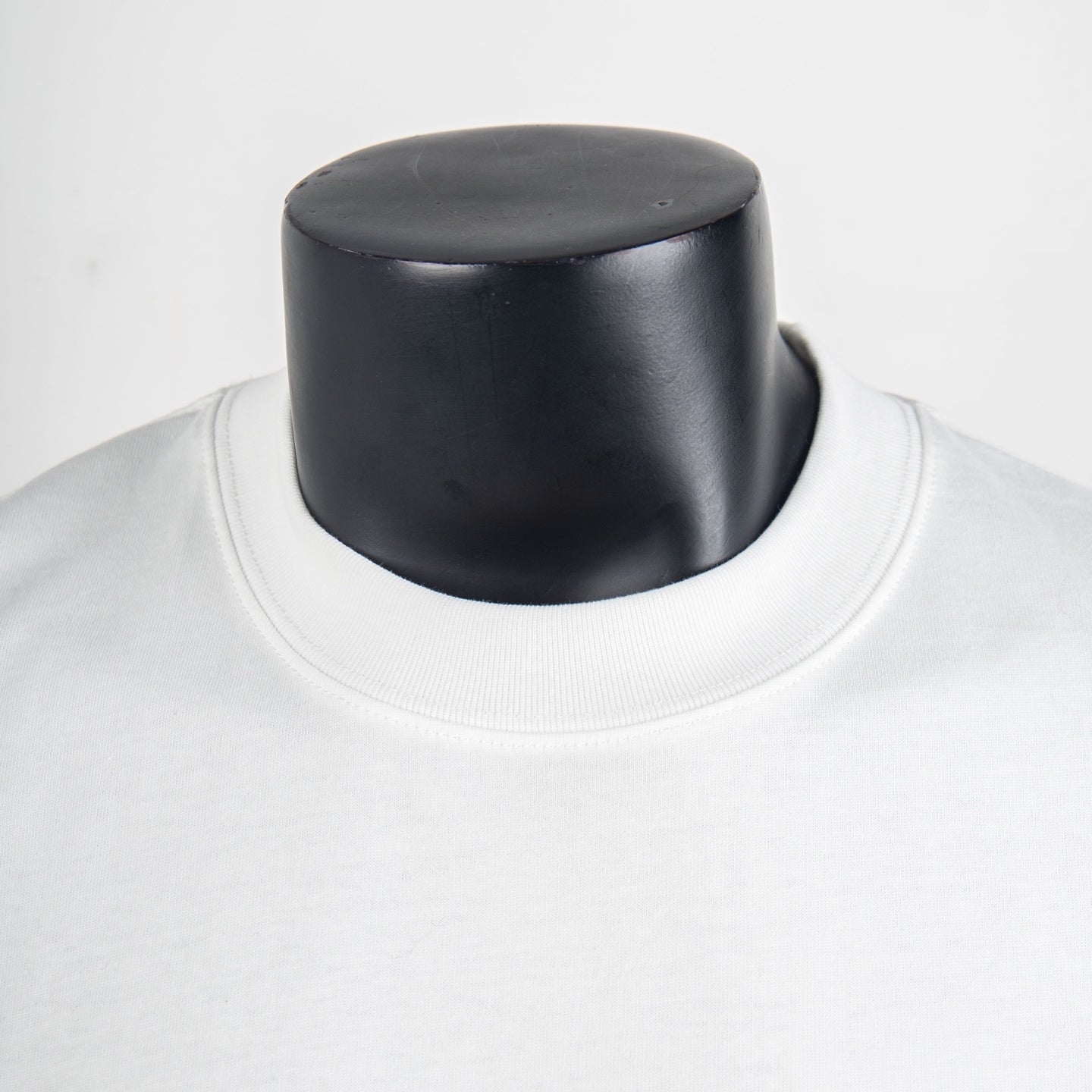 White short-sleeve T-shirt neckline close-up on black mannequin, crew collar