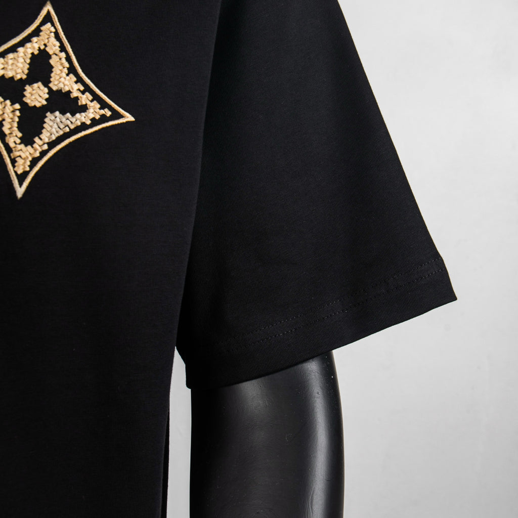 Louis Vuitton black T-shirt sleeve with partial gold logo at left chest