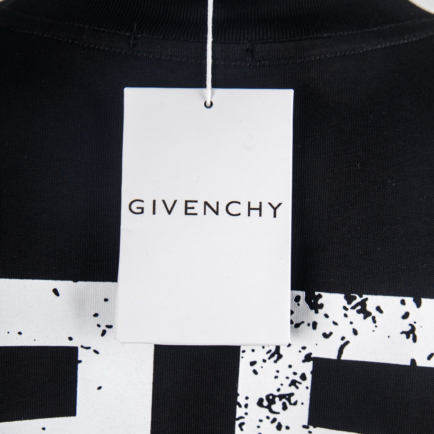 Black T-shirt with white hang tag at neckline reading Givenchy