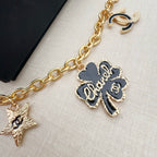 Gold-tone chain belt close-up with fleur-de-lis charm, heart accents, and stars