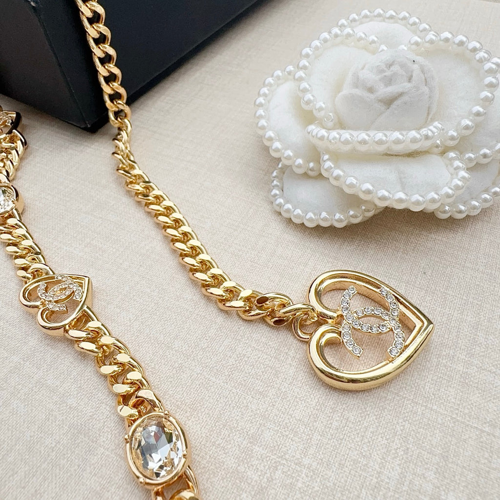 Chanel belt close-up with gold-tone heart pendant, crystal stones, and white flower detail