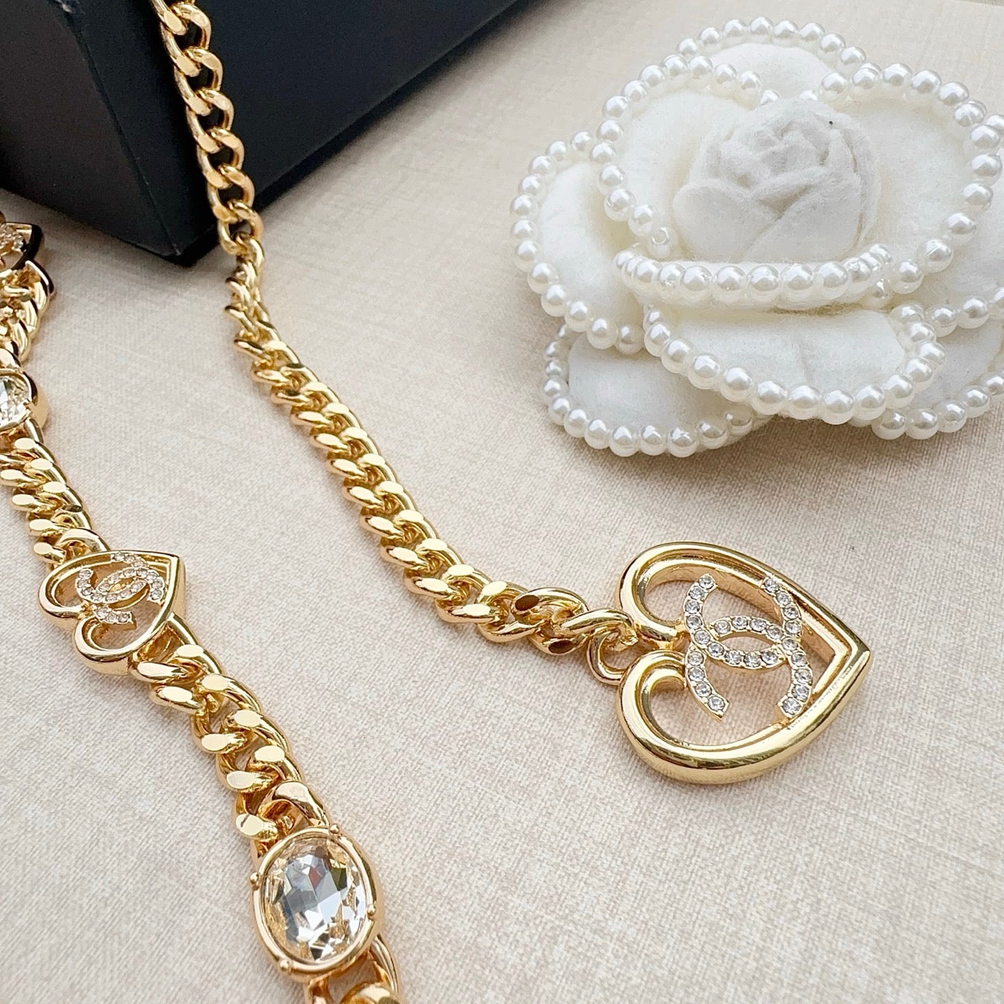 Chanel belt close-up with gold-tone heart pendant, crystal stones, and white flower detail