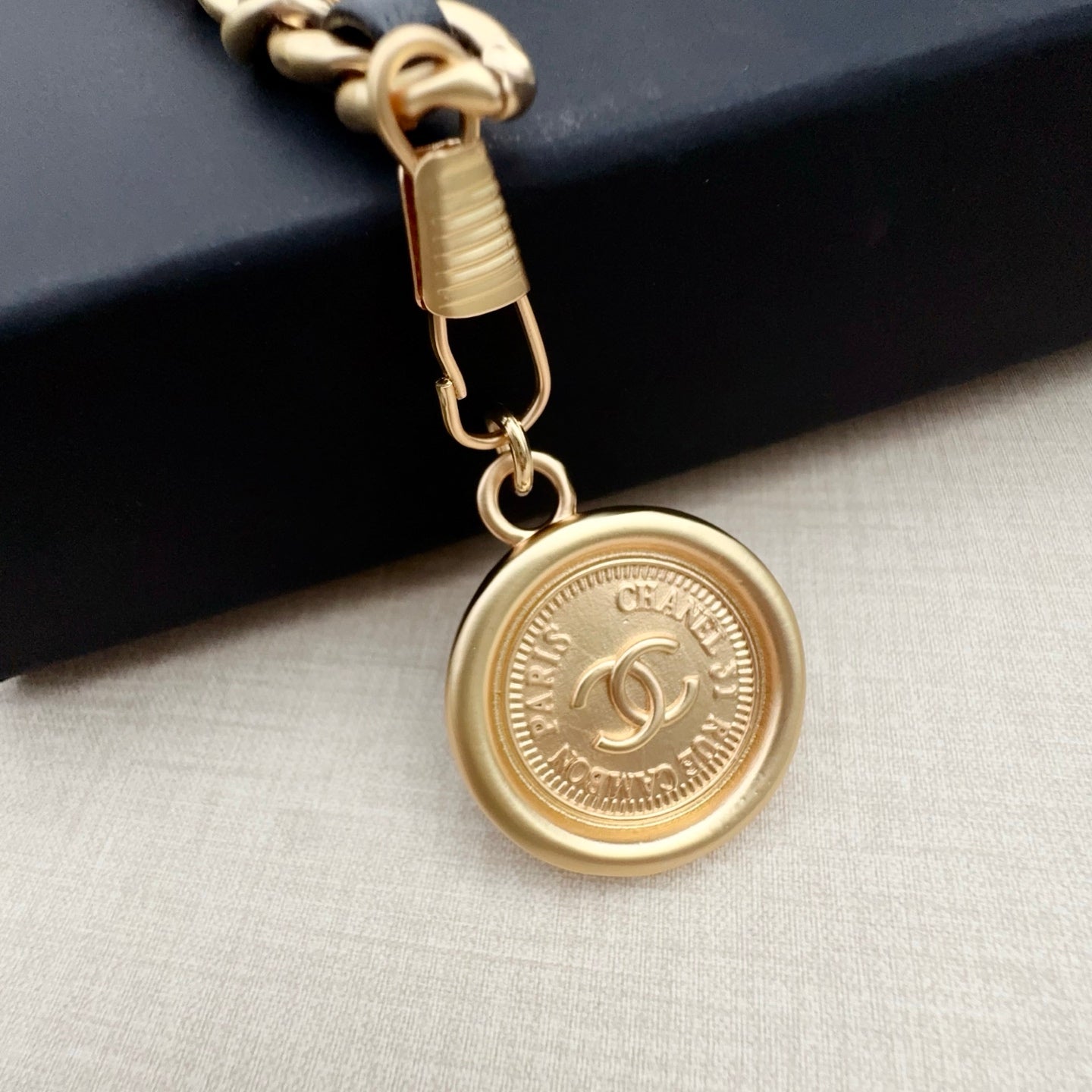 Gold-tone round logo pendant charm with clasp on chain belt