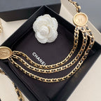 Gold-tone chain belt with round logo medallion charms on black pouch