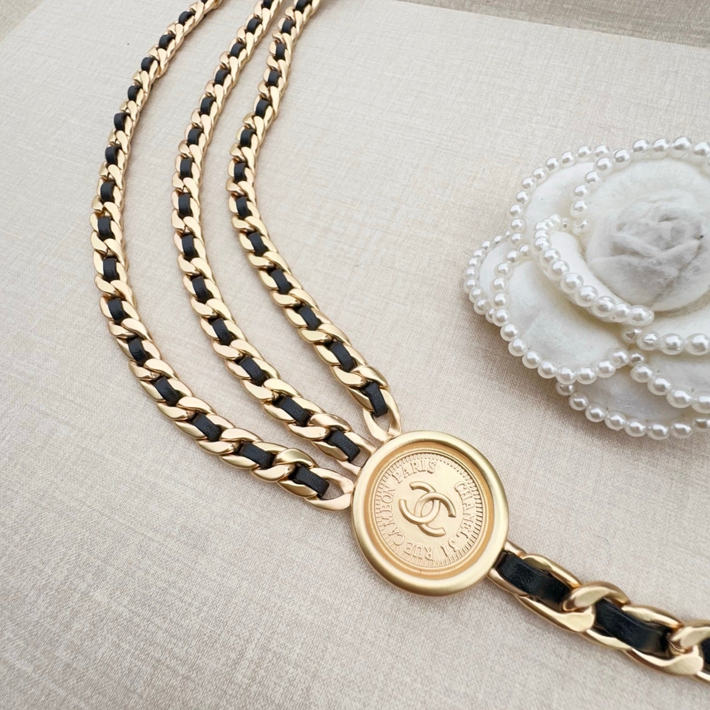 Gold-tone chain belt with round logo coin charm and braided chain strands