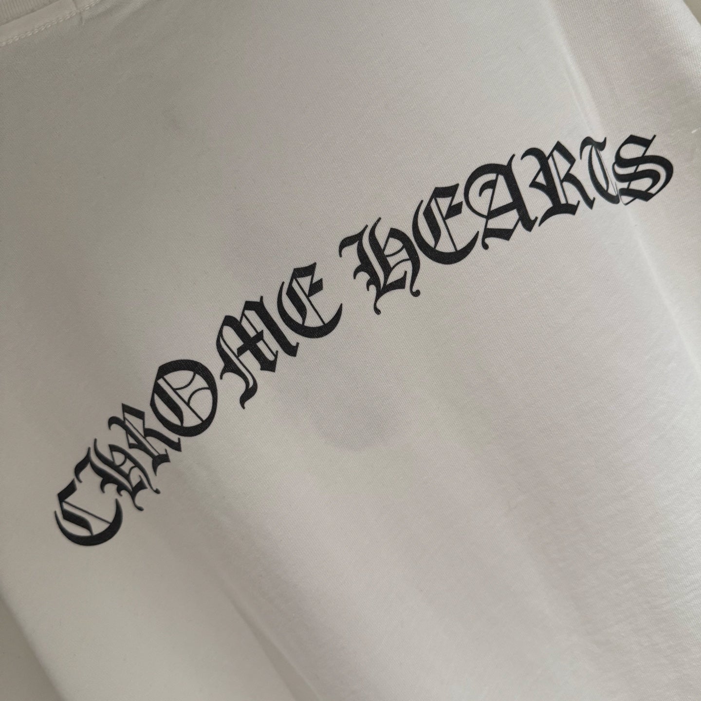 Close view of black logo text on white short-sleeve T-shirt