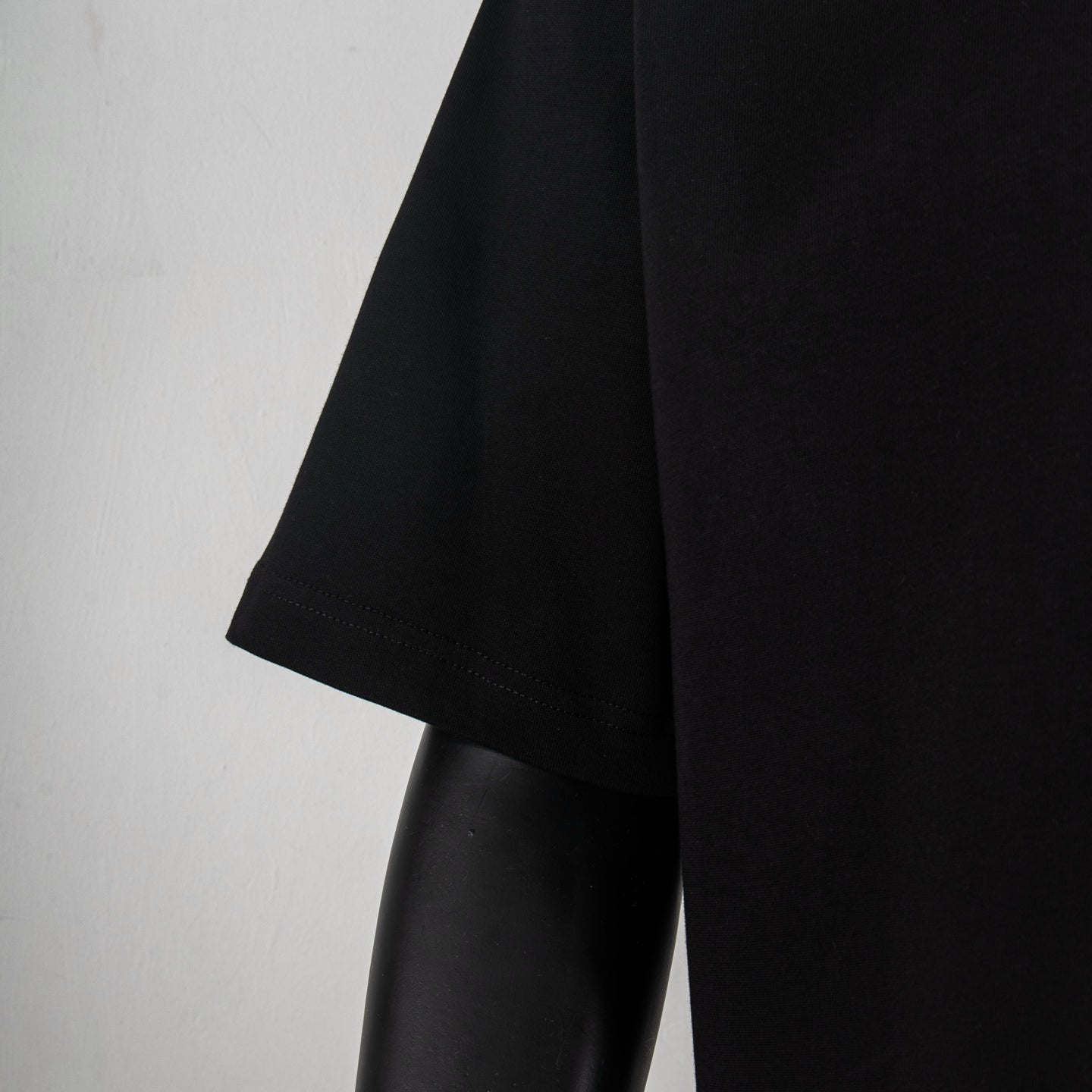 Black T-shirt side view with short sleeve hem and curved bottom