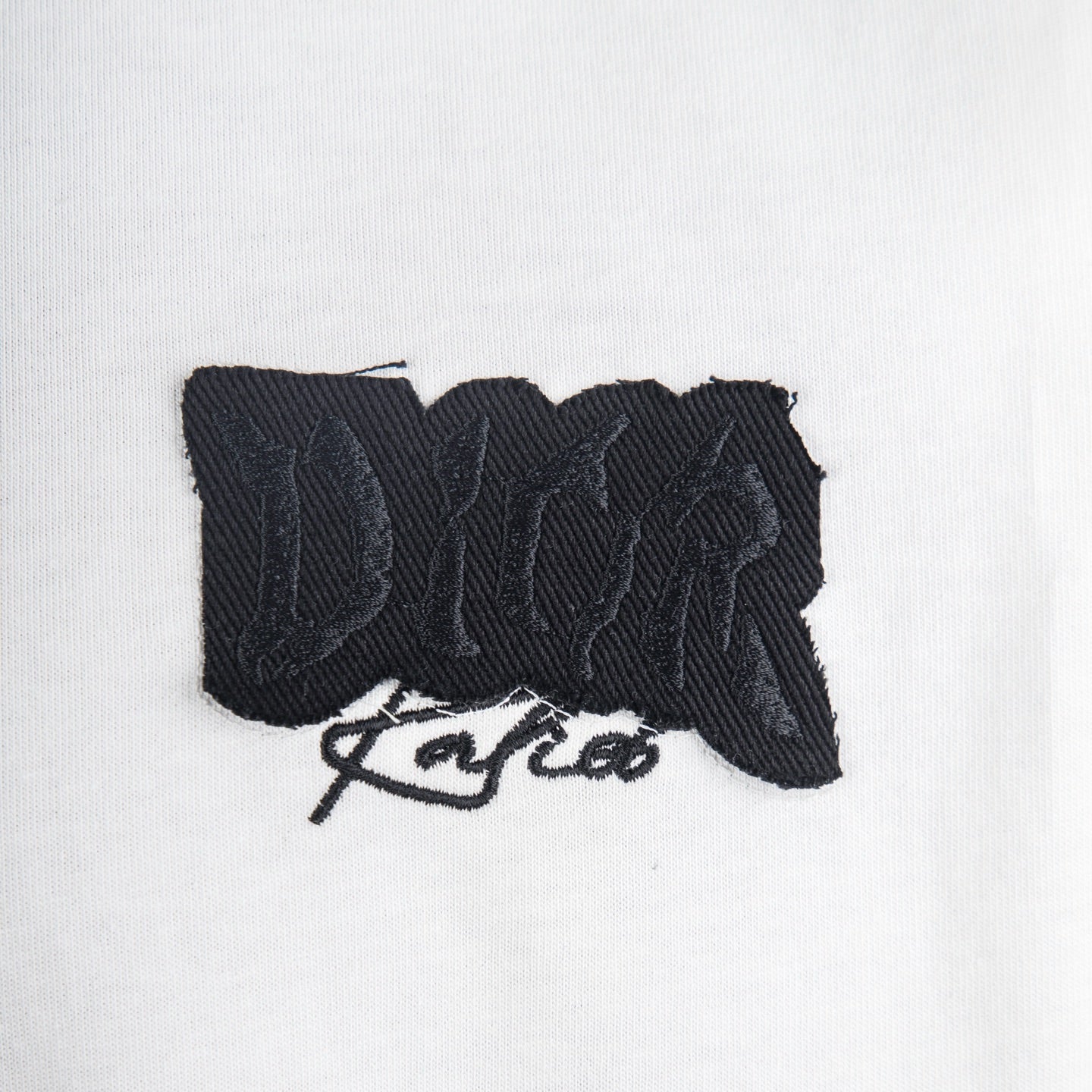 Close-up of black textured logo graphic on white T-shirt chest