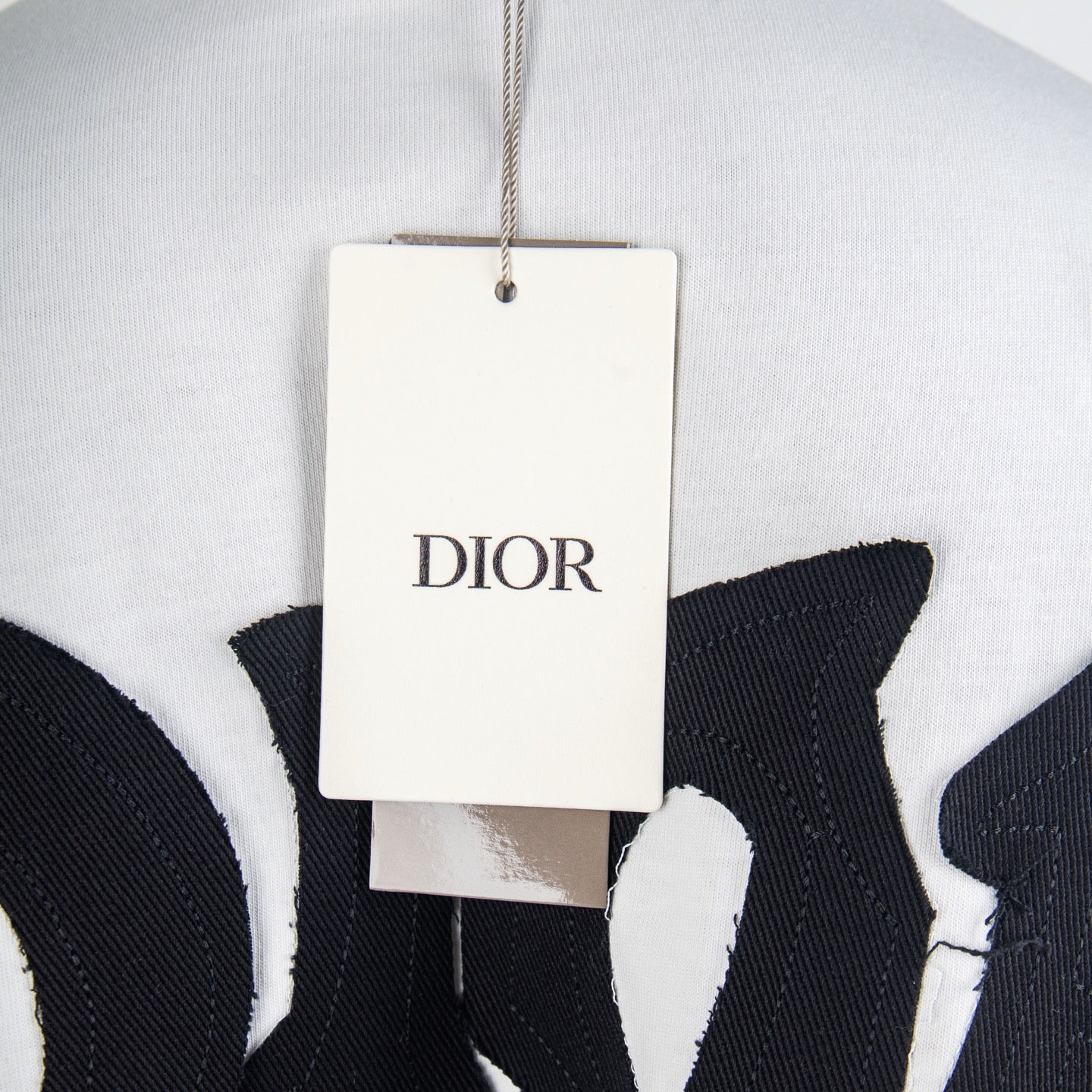 White T-shirt with hanging Dior brand tag near neckline