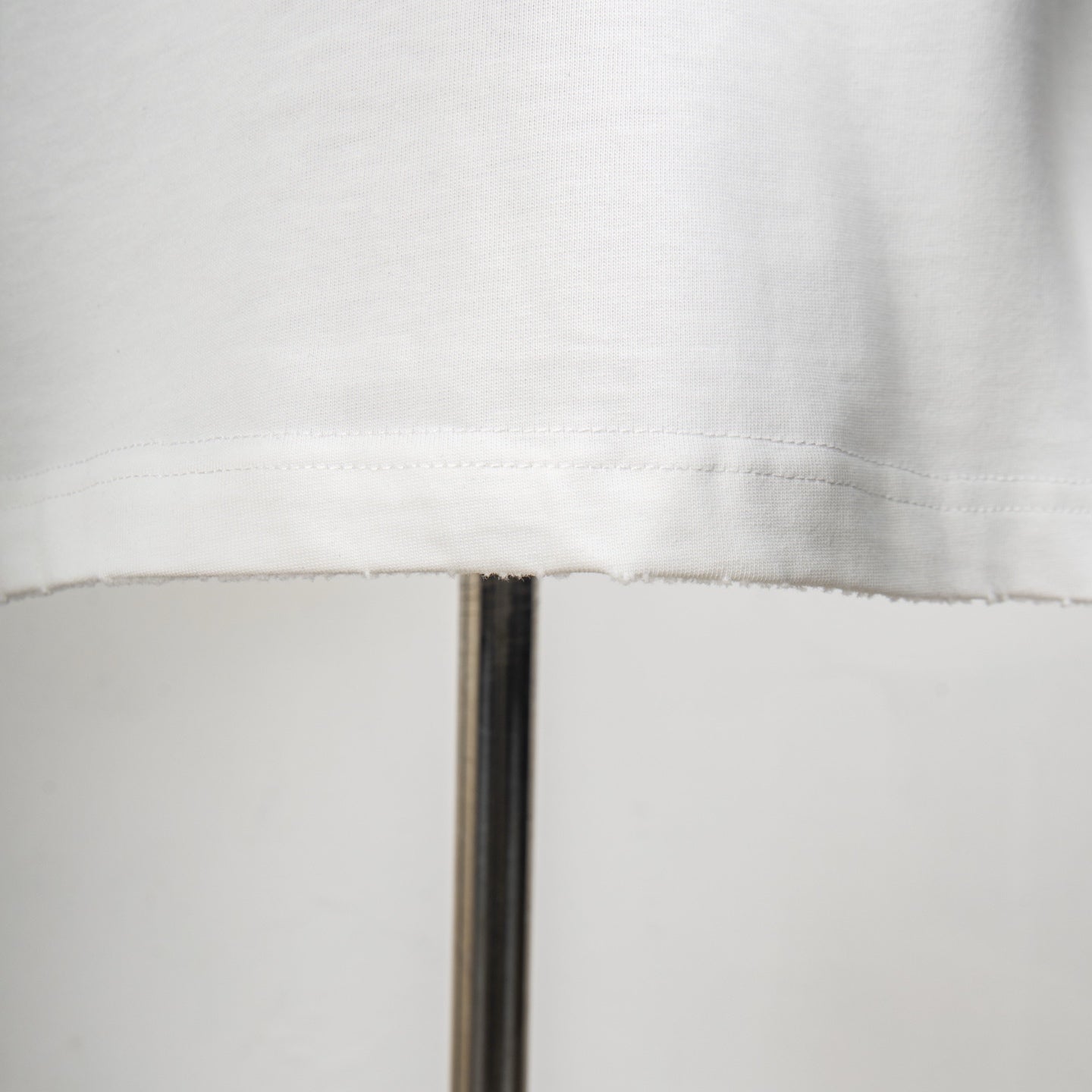 White T-shirt hem stitching detail at mid-body