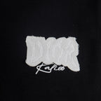 Black T-shirt with small white Dior logo patch on left chest