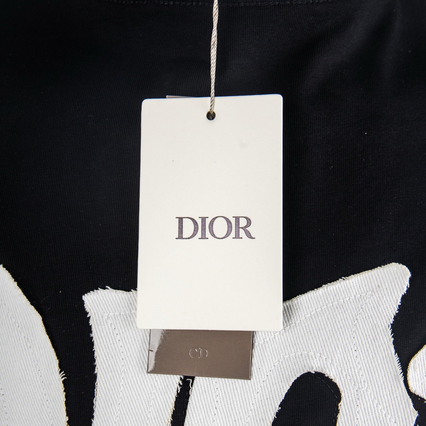 Black T-shirt with hanging white Dior tag near neckline.