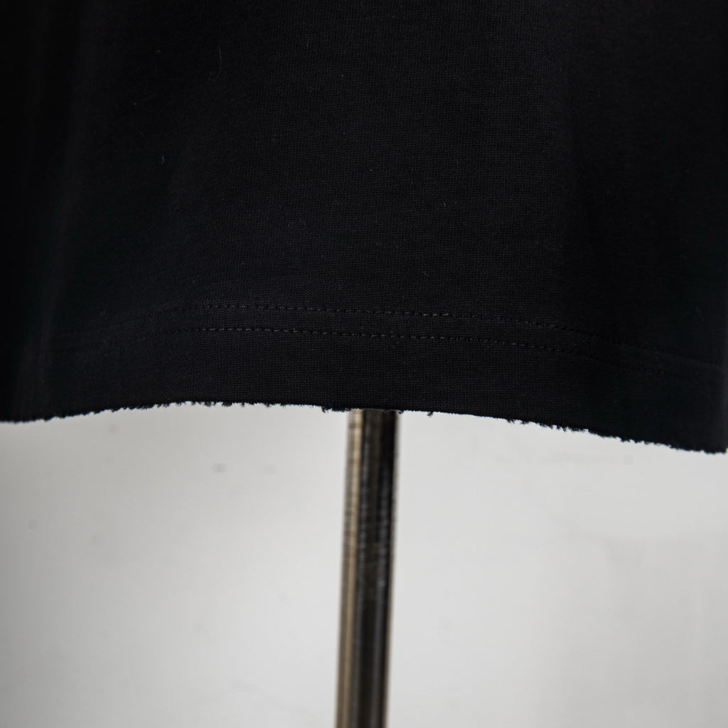 Black T-shirt hem with visible stitching and slightly uneven edge.
