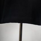 Black T-shirt hem with visible stitching and slightly uneven edge.