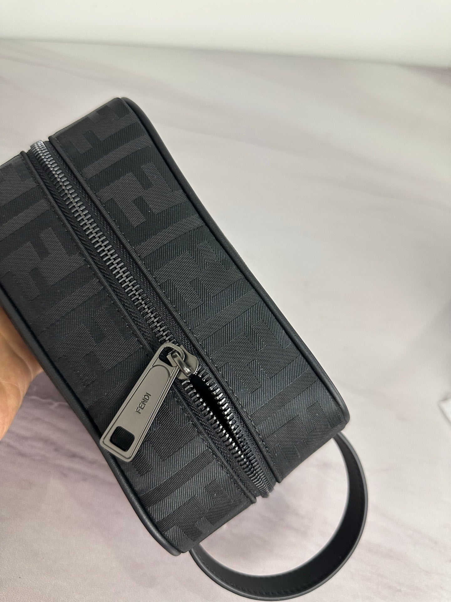 Fendi crossbody bag side close-up, dark monogram fabric, metal zipper pull