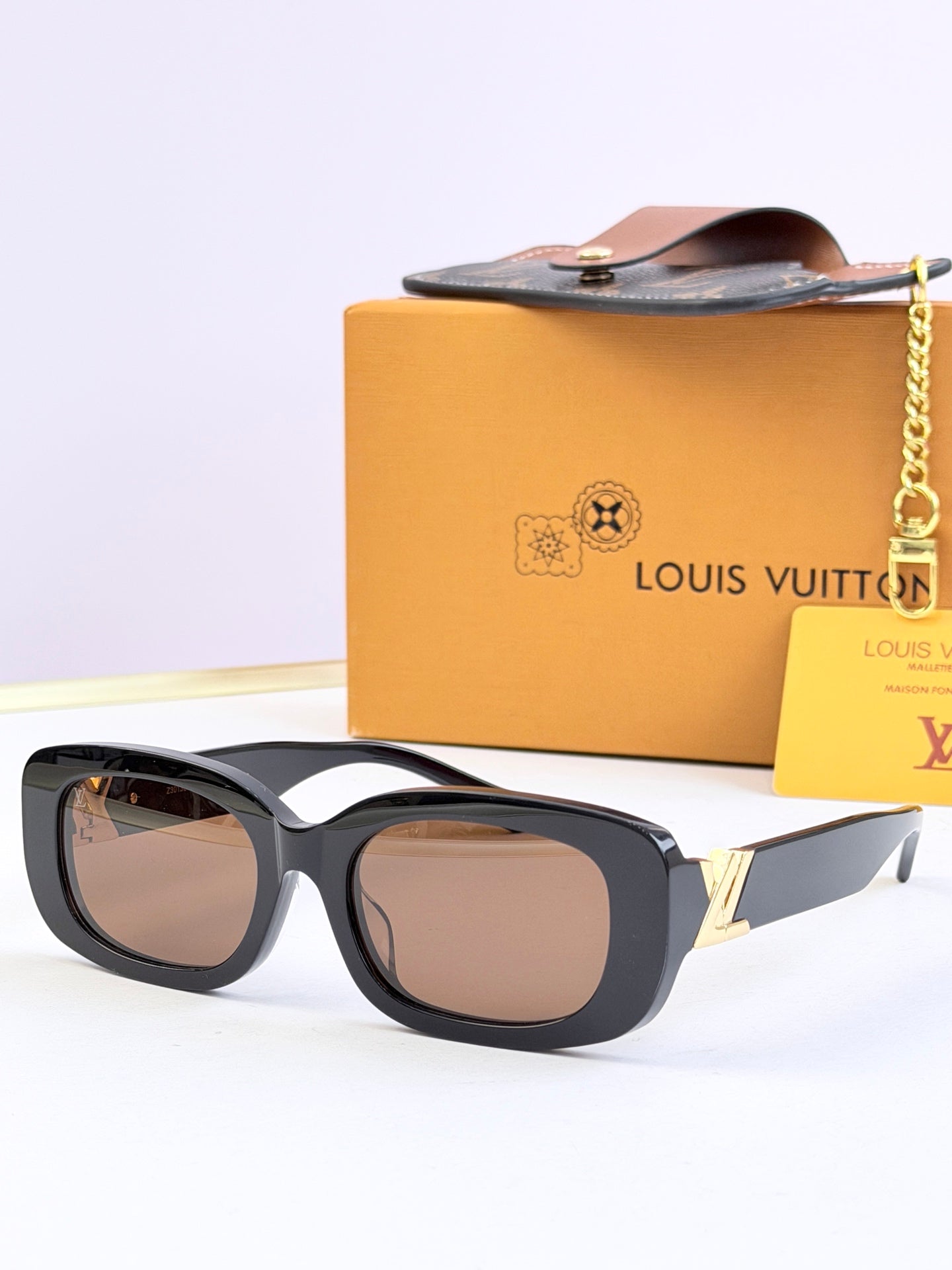 Louis Vuitton sunglasses with dark frames and warm brown-tinted lenses, gold temple accents.