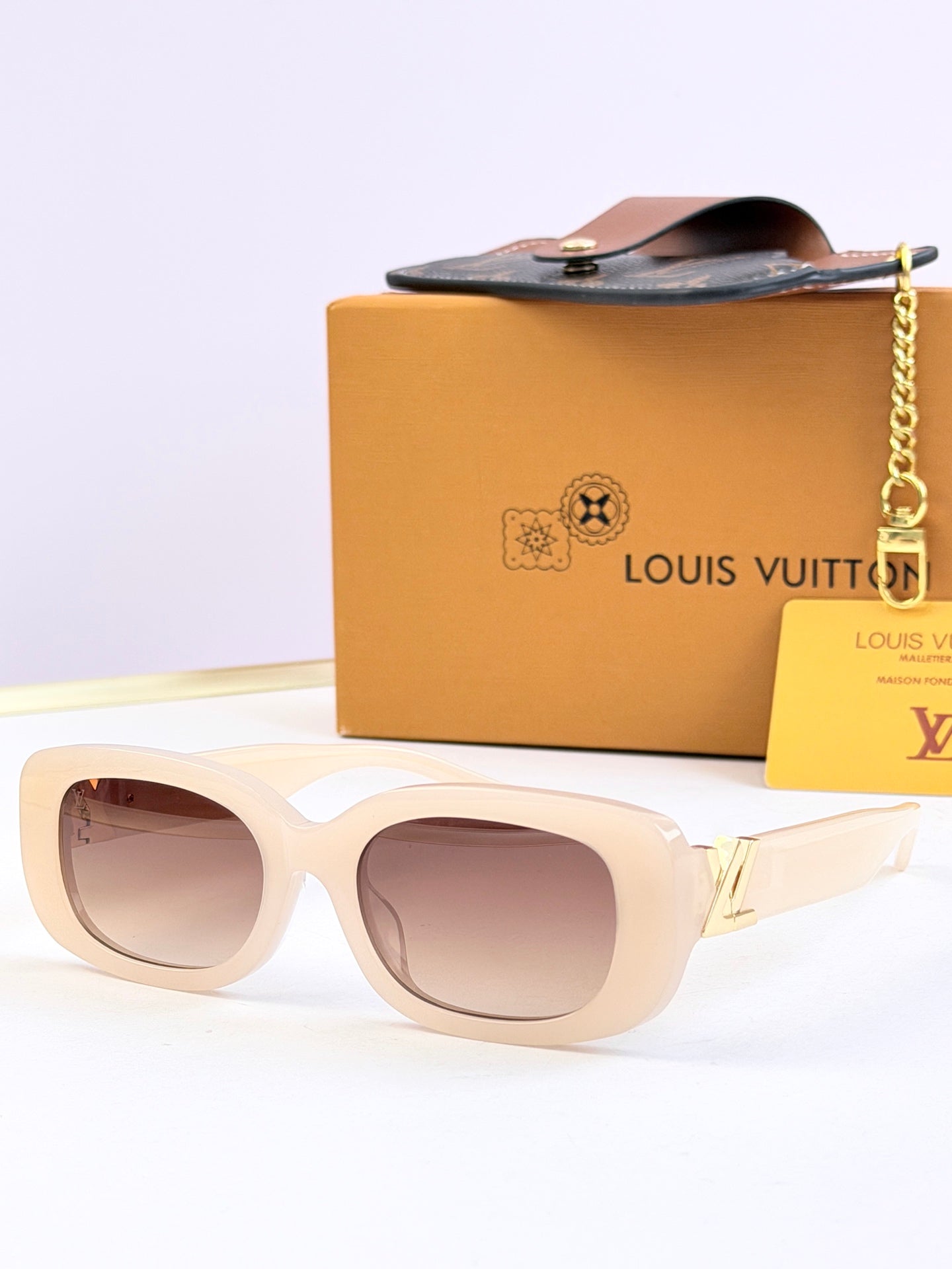 Louis Vuitton sunglasses, light beige frames with brown-tinted lenses and gold logo detail.