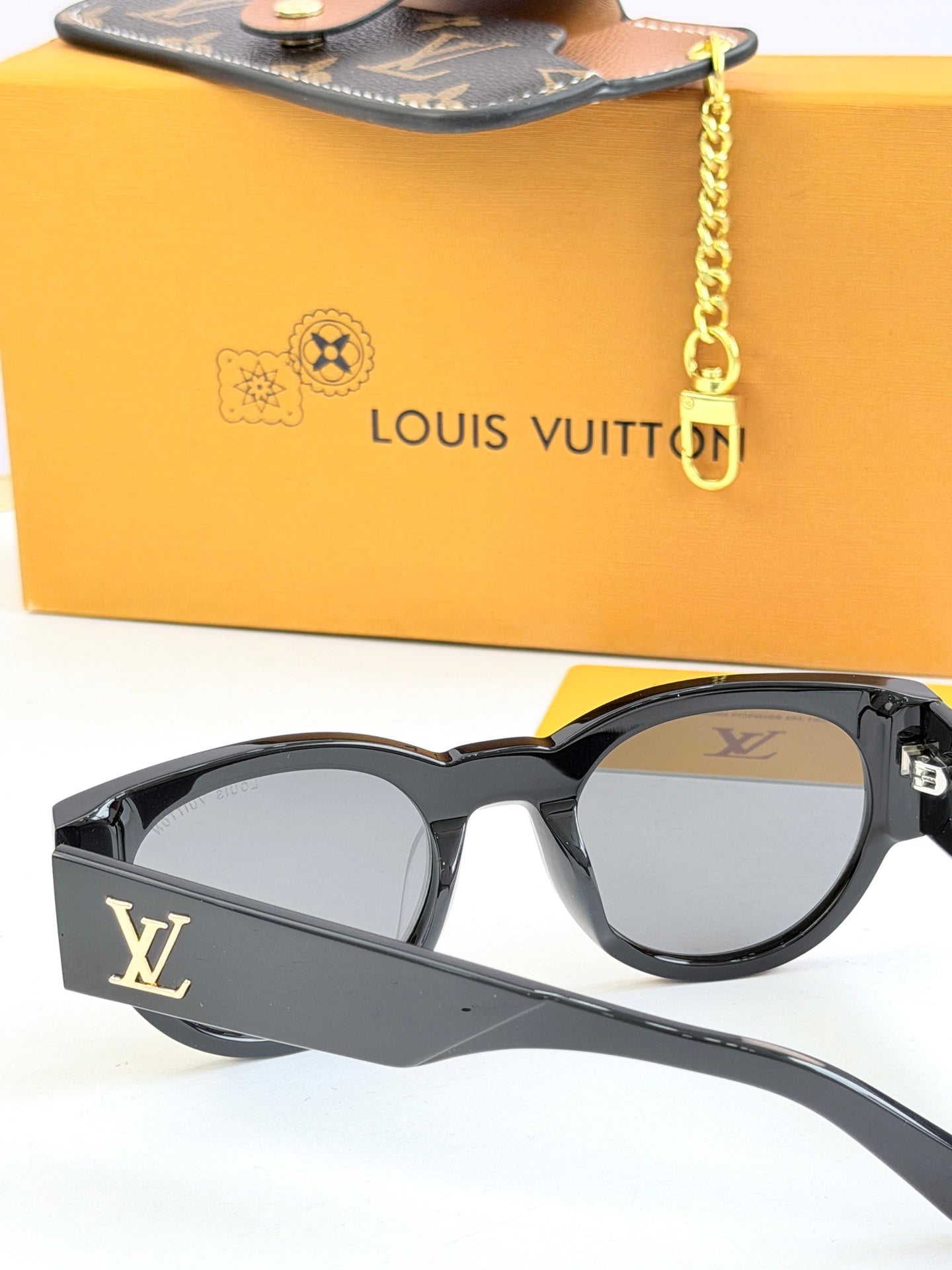 Louis Vuitton black sunglasses close-up with LV side logo and gray tinted lenses