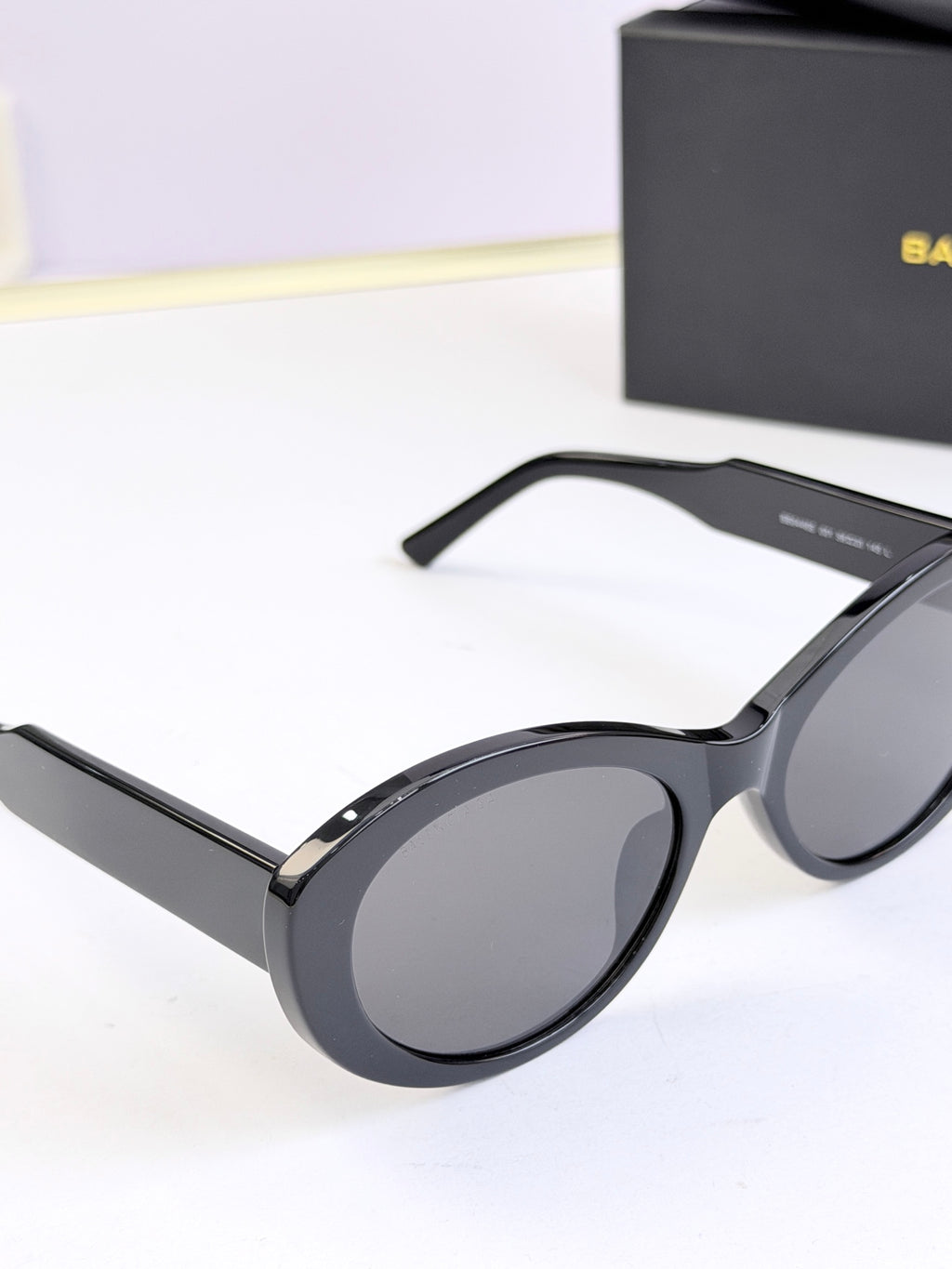 Black round sunglasses from side view with gray lenses and curved temples