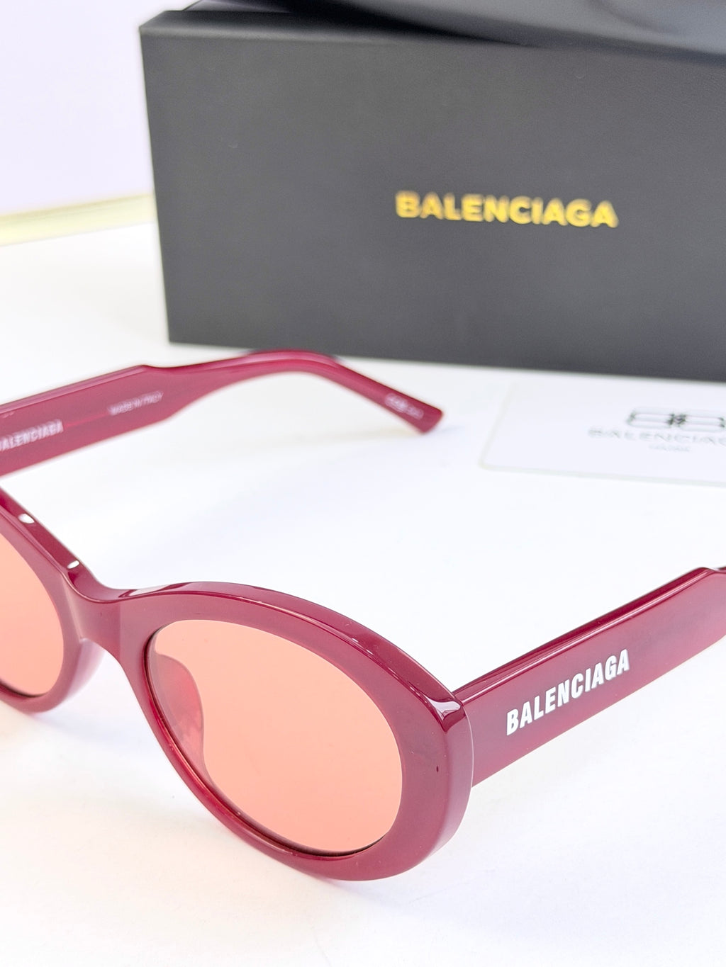 Pink round sunglasses close-up with peach lenses and BALENCIAGA logo on lens frame
