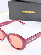 Pink round sunglasses close-up with peach lenses and BALENCIAGA logo on lens frame