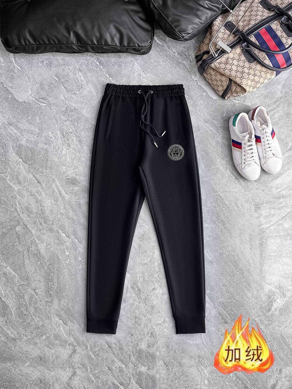 Black jogger pants with elastic waistband and drawstring, circular logo patch