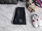 Black jogger pants with elastic waistband, drawstring, and circular logo patch