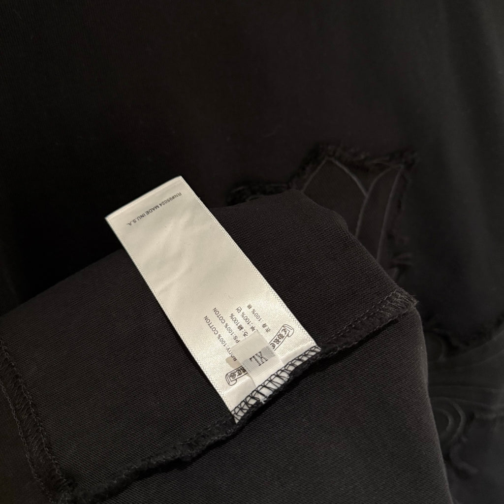 Black T-shirt sleeve cuff with fabric label tag visible near hem