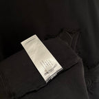 Black T-shirt sleeve cuff with fabric label tag visible near hem