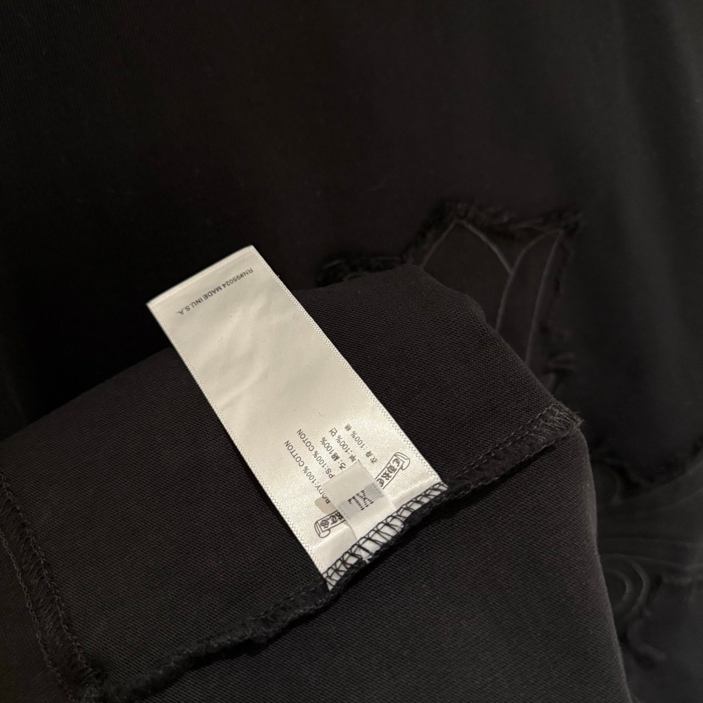Black T-shirt sleeve cuff with fabric label tag visible near hem