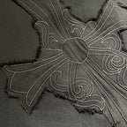 Embroidered cross flower design on black T-shirt fabric with textured stitching