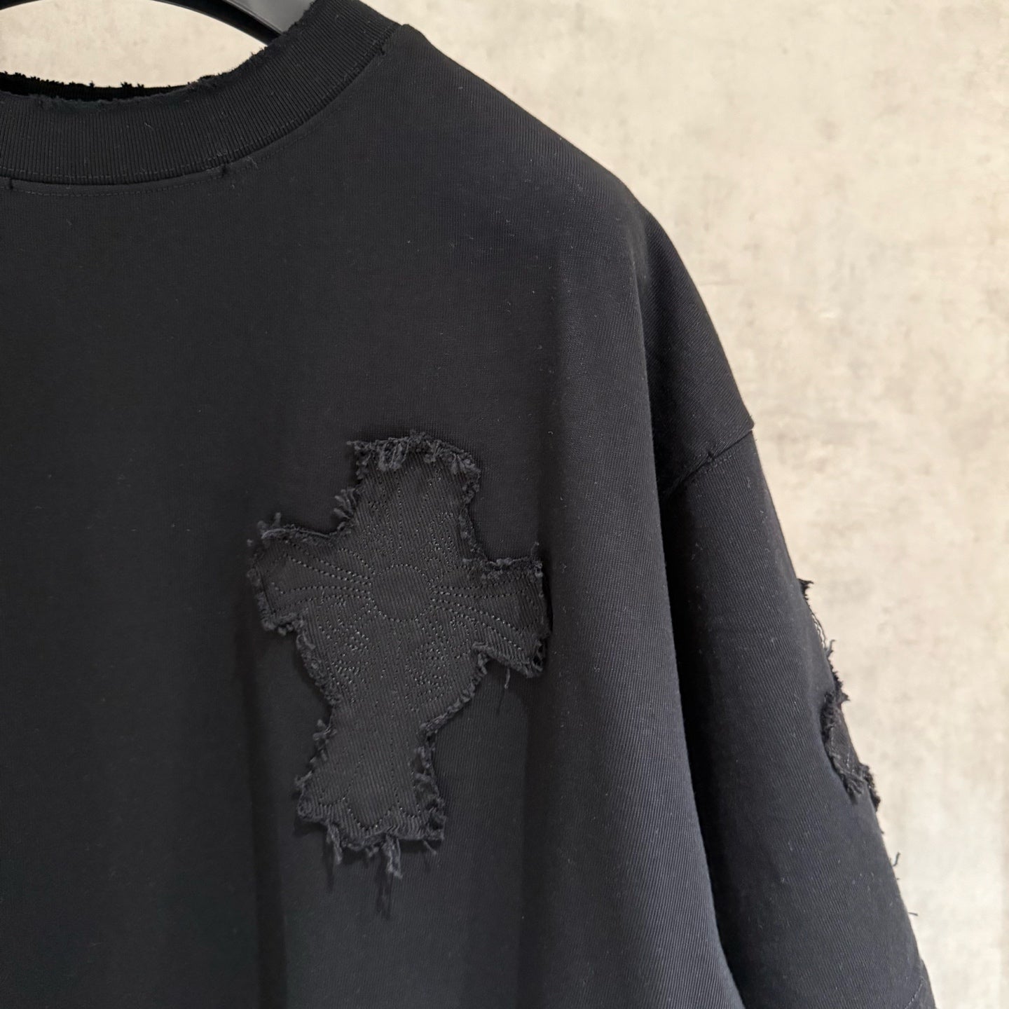 Black short-sleeve T-shirt close-up of chest cross applique with frayed edges