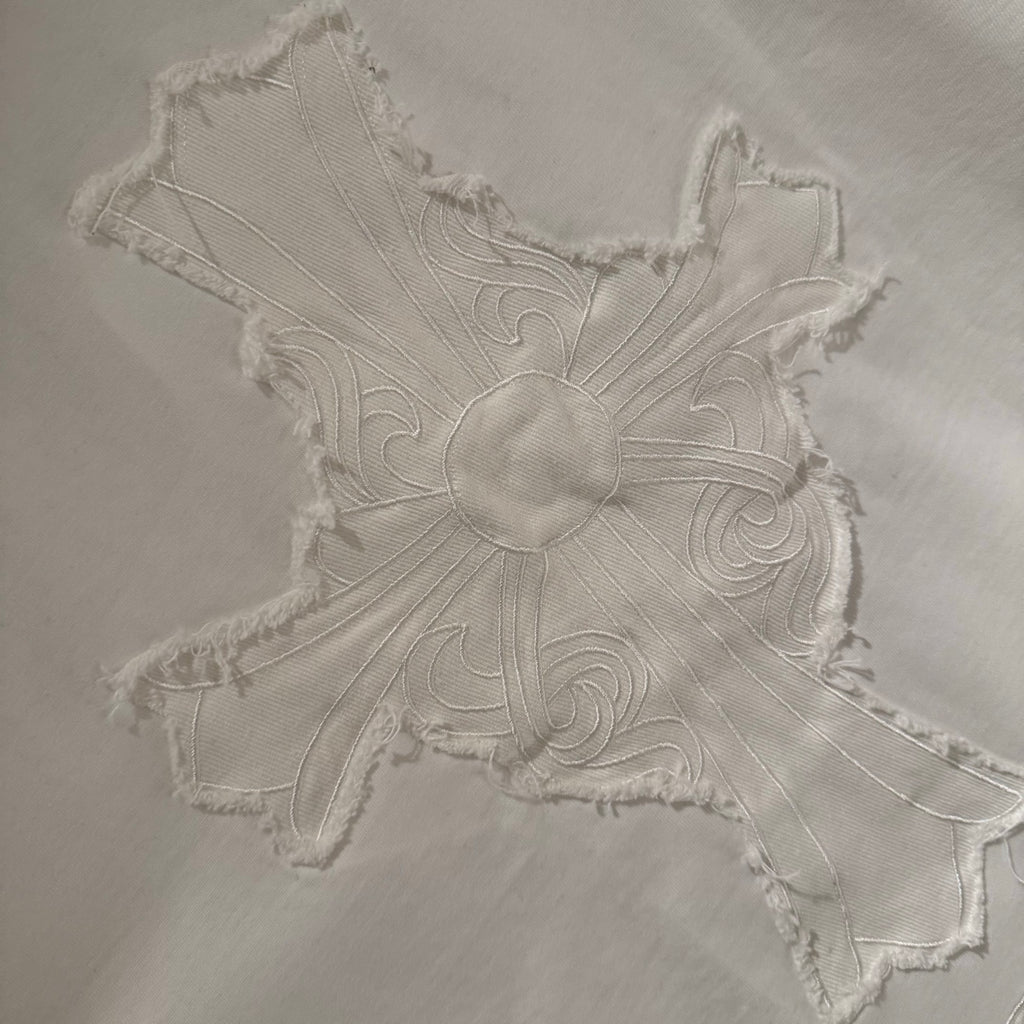 Embroidered cross applique on a white short-sleeve T-shirt